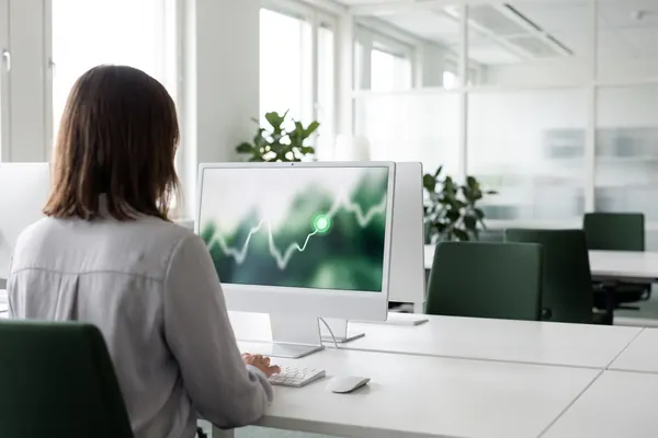 AI-generated image: Employee seen from behind in front of a screen with a trend line