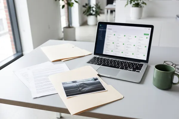 Claim documents with a photo of a damaged car next to a laptop